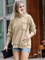 Woman wearing a beige hoodie and denim shorts outdoors.