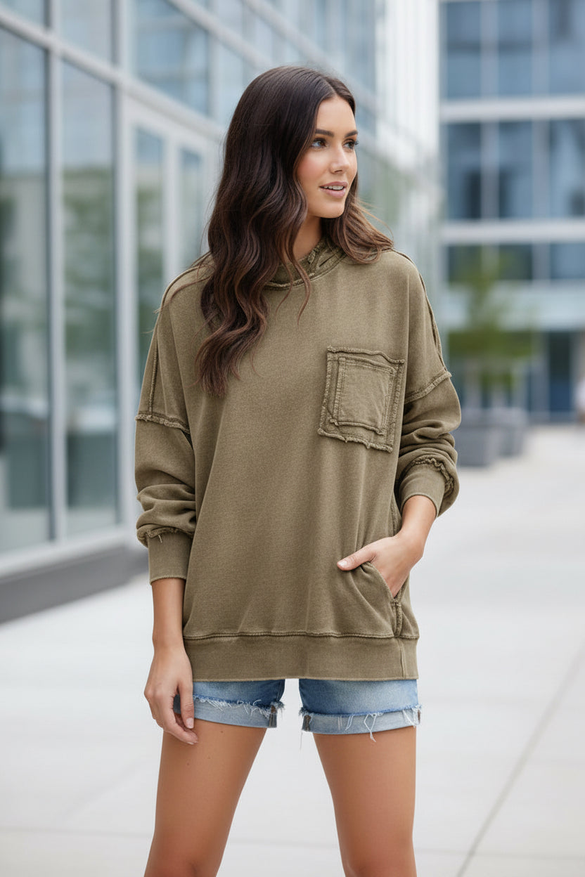 Woman wearing a beige hoodie and denim shorts outdoors.
