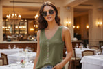 Woman wearing a green sleeveless button-up top outdoors