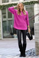 Woman wearing a bright pink sweater, black leather pants, and black boots outdoors.