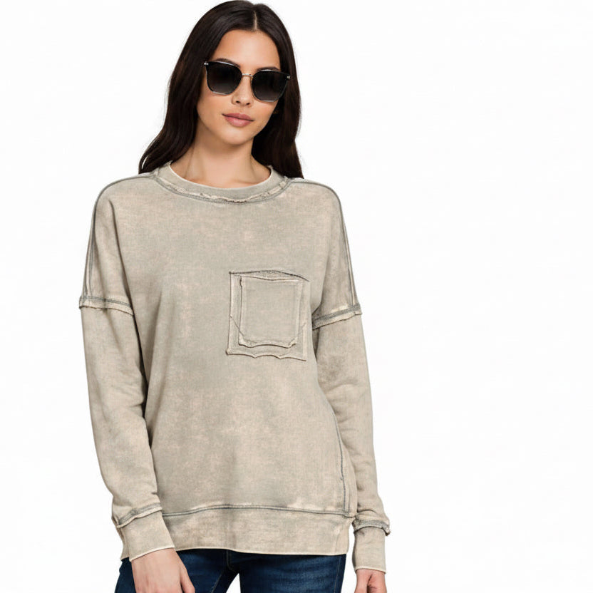Woman wearing a beige distressed sweatshirt with a pocket on a white background