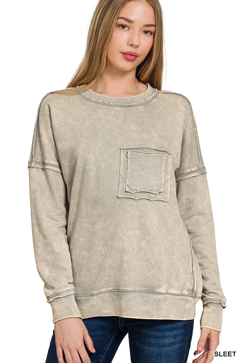 Woman wearing a beige distressed sweatshirt with a pocket on a white background