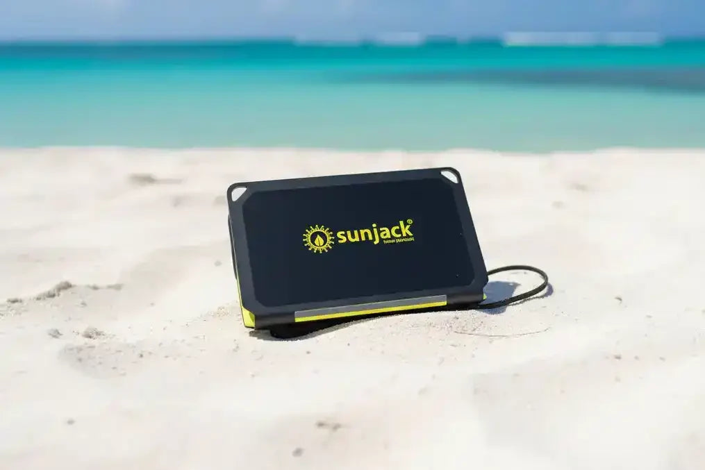 SunJack portable solar charger on sandy beach with ocean view