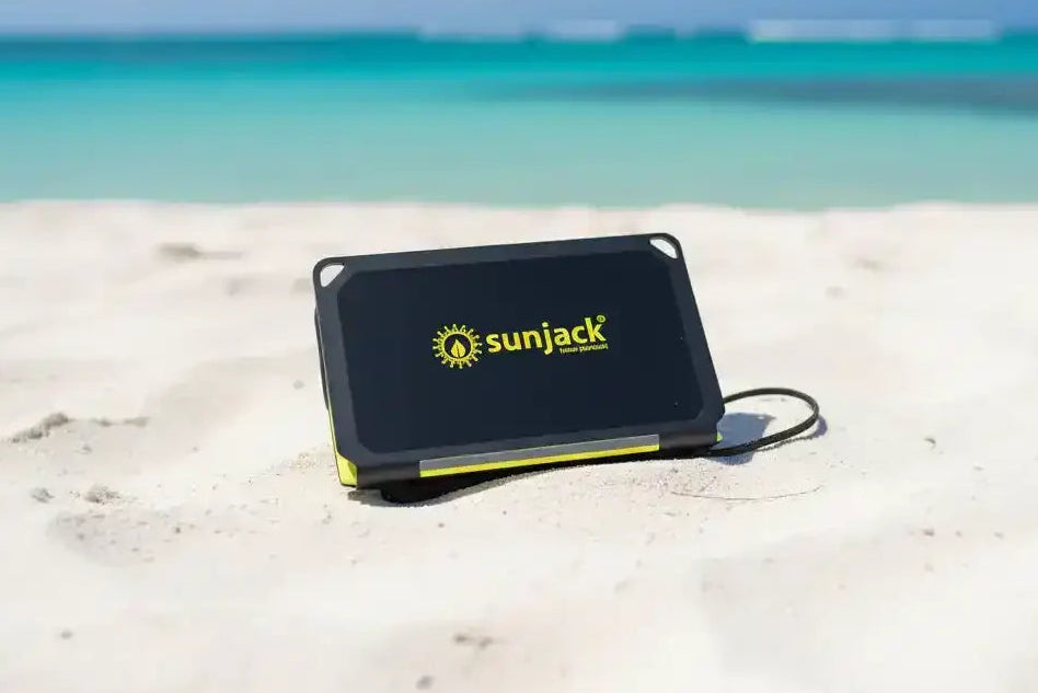 SunJack portable solar charger on sandy beach with ocean view