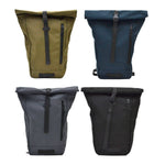 Four roll-top backpacks in olive, navy, gray, and black with front zipper pockets and buckle straps