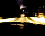 Night driving view from car, headlights illuminating wet road, blurred motion, dark trees, distant lights