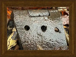 Rusty metal hinge with three holes, nestled among autumn leaves, framed in wood