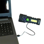 Black LitezAll COB LED flashlight charging via USB cable connected to laptop, showing battery level indicator.