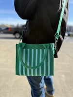 Green and white striped tote bag with shoulder strap, carried outdoors