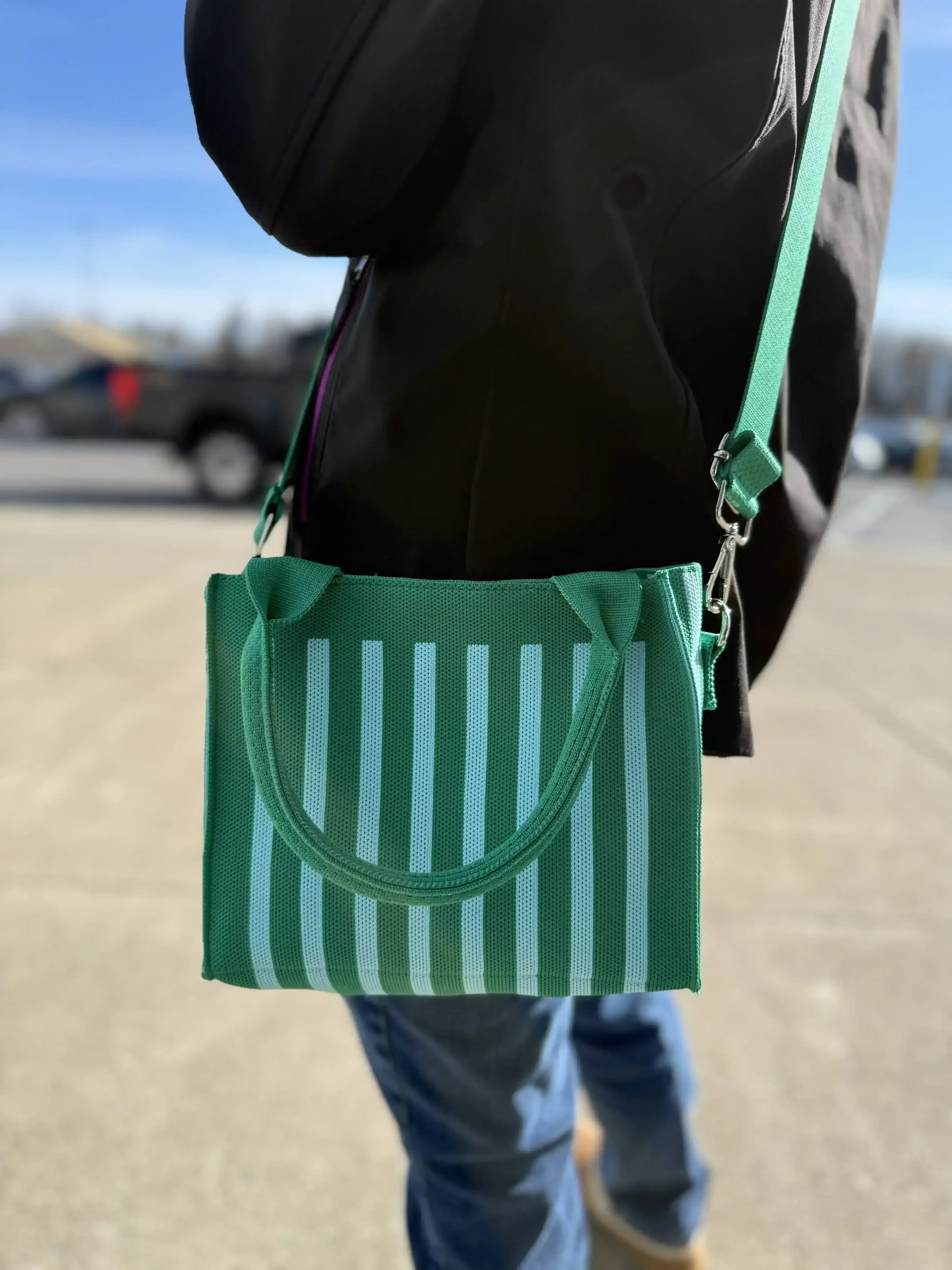 Green and white striped tote bag with shoulder strap, carried outdoors